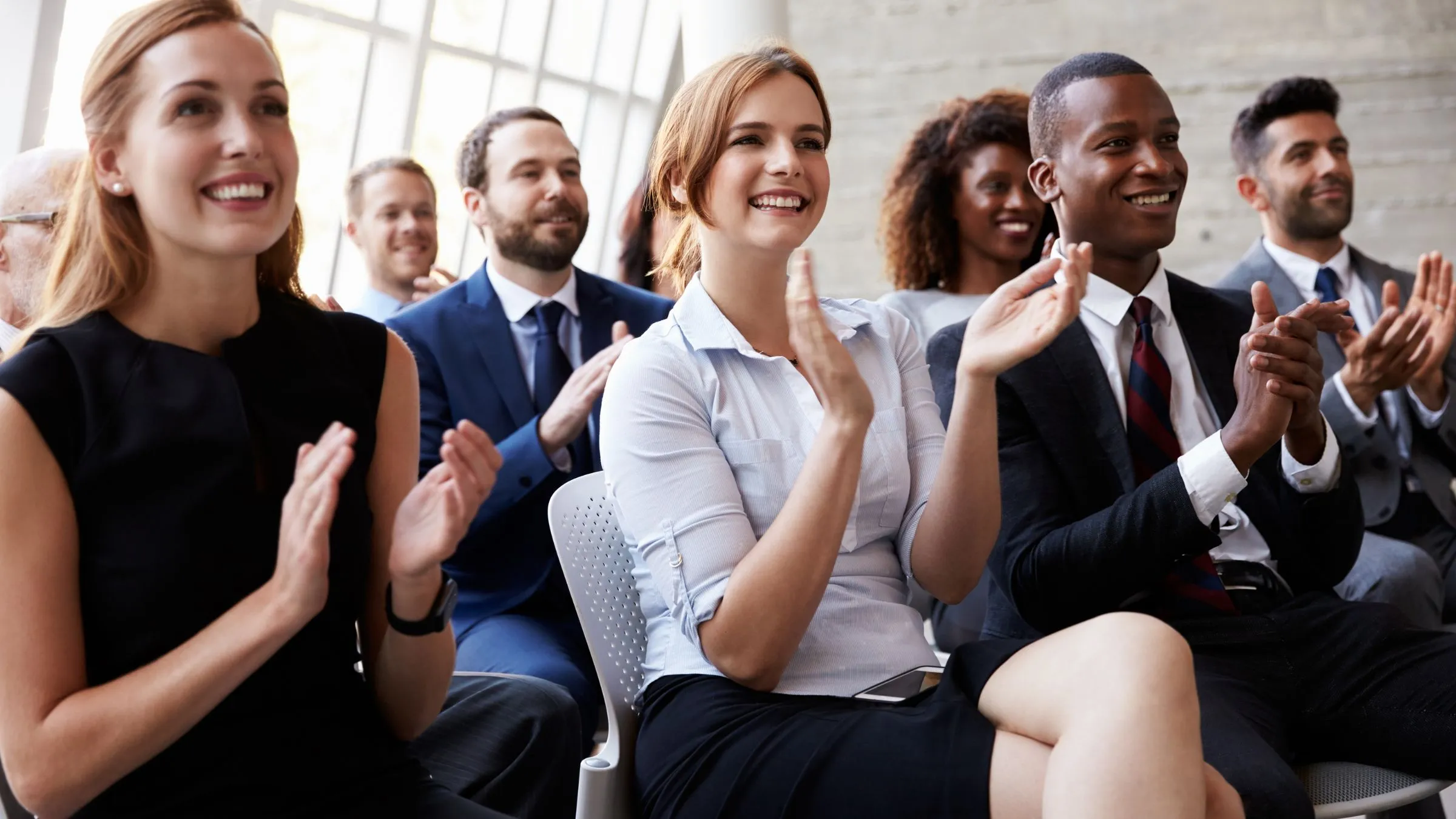 A conference audience smiling and applauding.