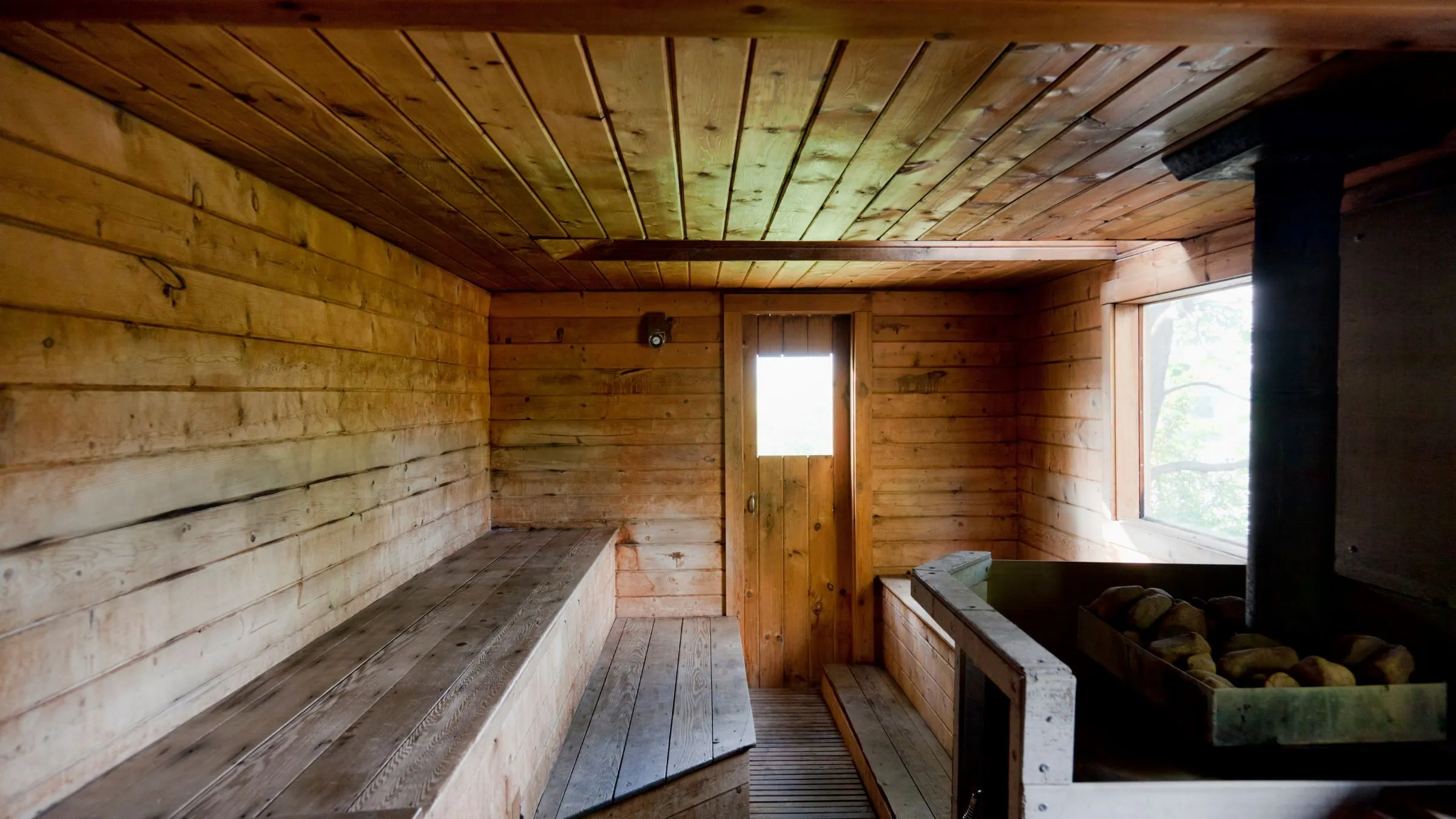 An empty wooden sauna with benches and a small window.