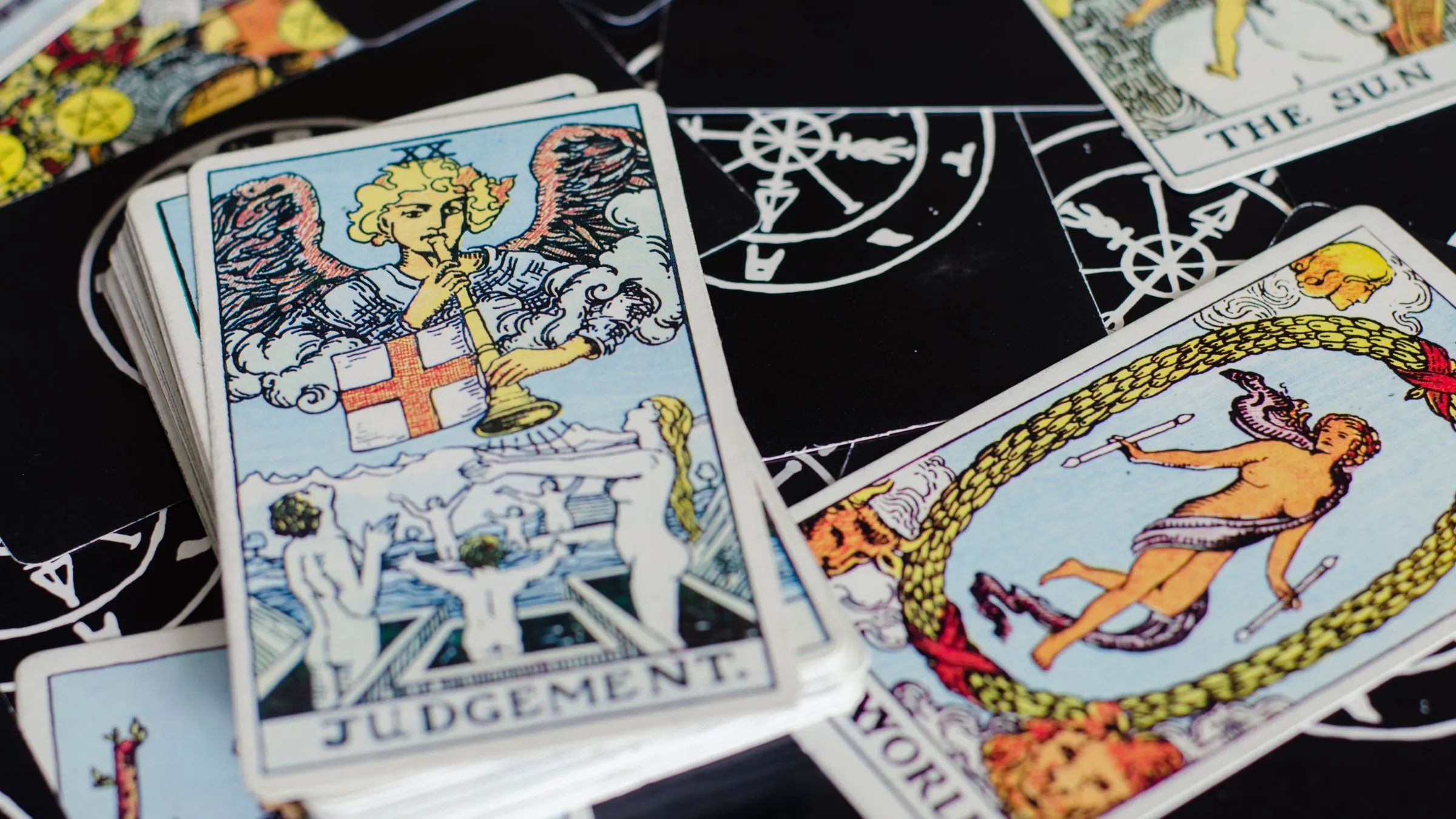 The Judgement tarot card next to The World card on a dark table.