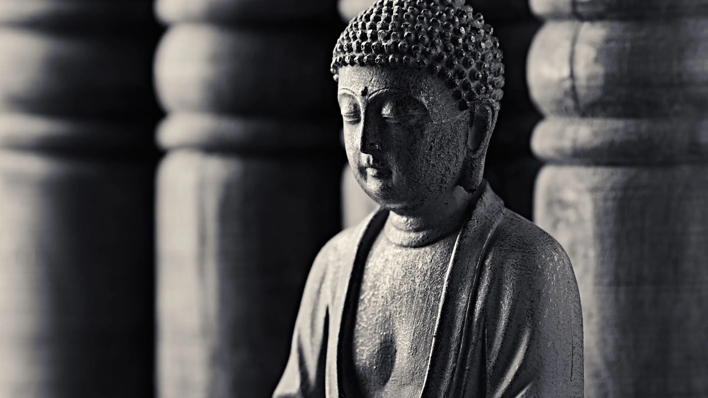 A black and white close-up of a seated Buddha statue.