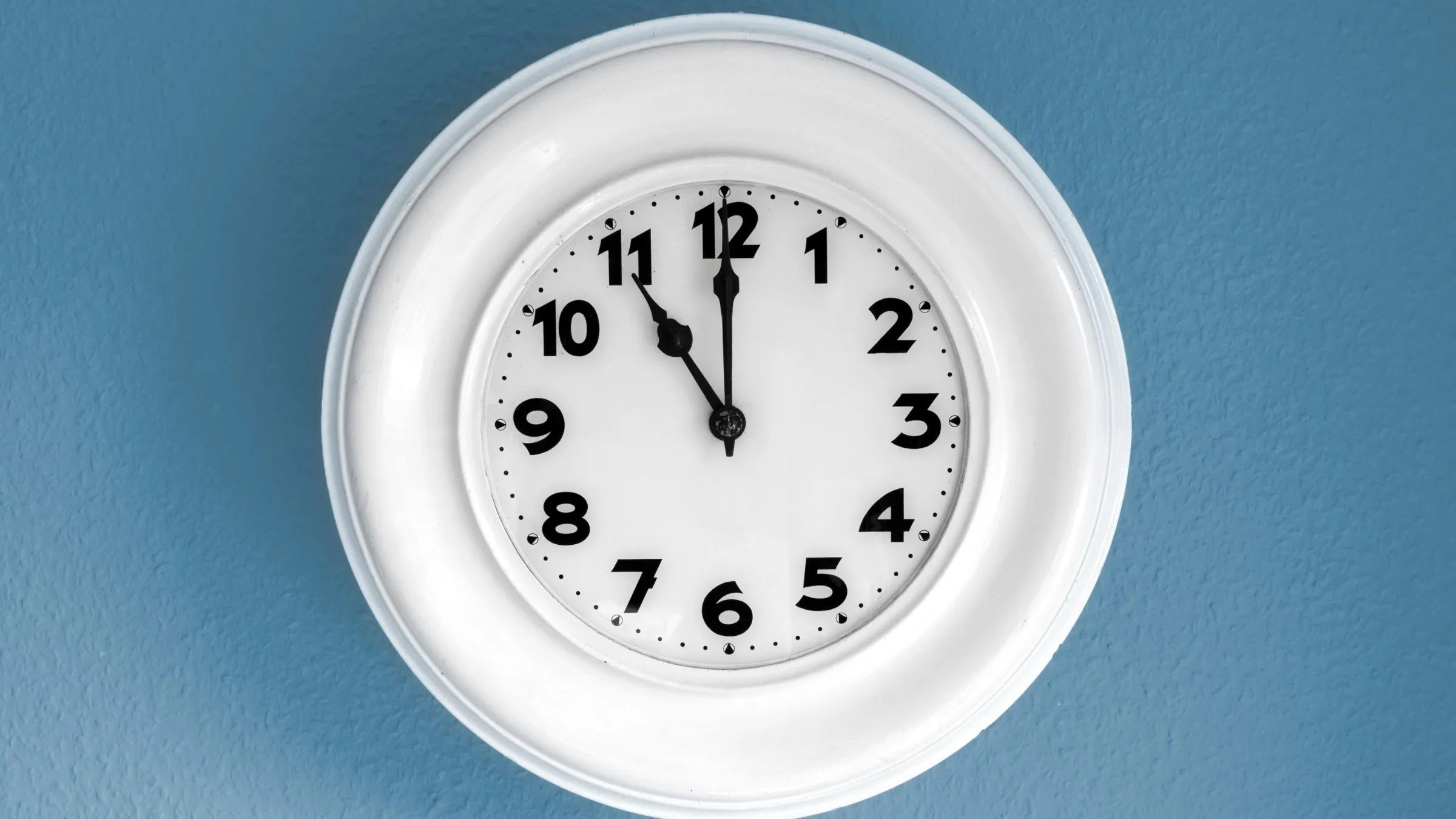 A white wall clock on a blue background.